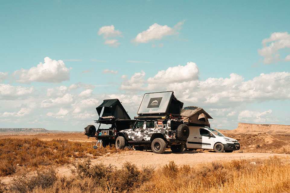 Trois tentes de toit sur des véhicules 4X4 au milieu du désert, dans la nature.