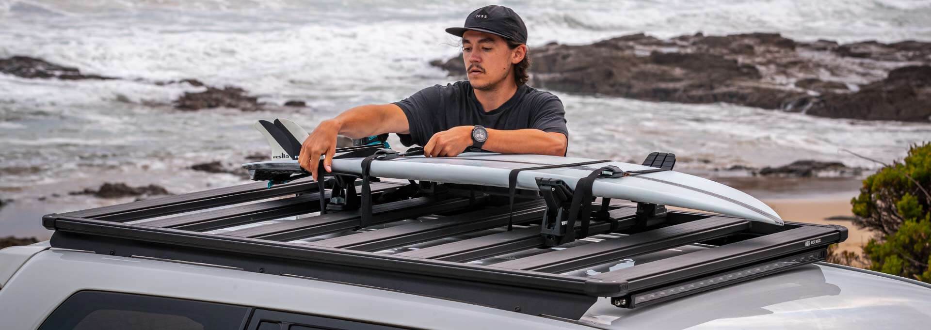 Planche de surf fixée sur une galerie ARB BASE Rack au bord de la mer