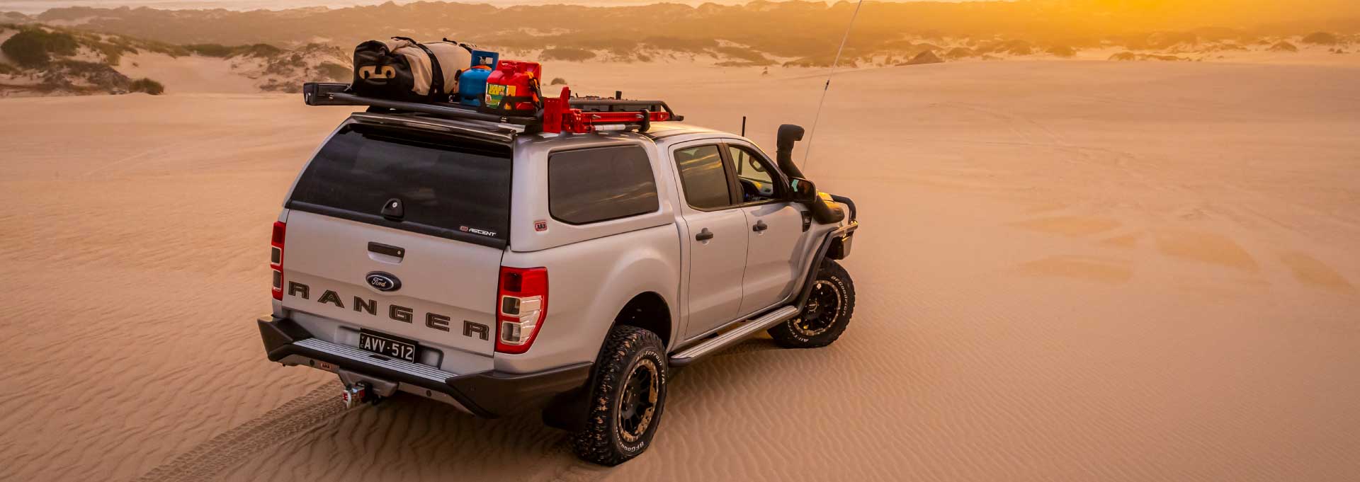 Ford Ranger avec hardtop ARB et galerie chargée au-dessus de la benne dans les dunes
