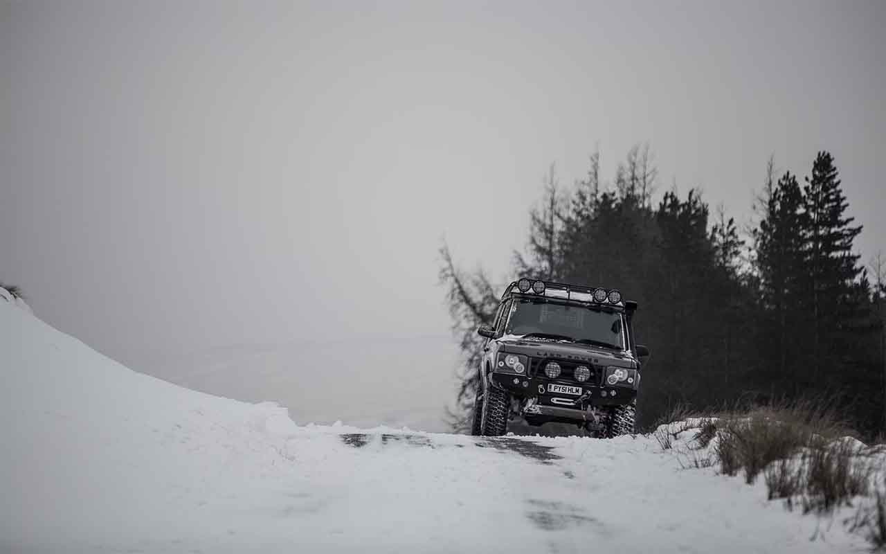 Land Rover discovery en offroad dans une zone enneigée, équipé de pneus tout terrain.